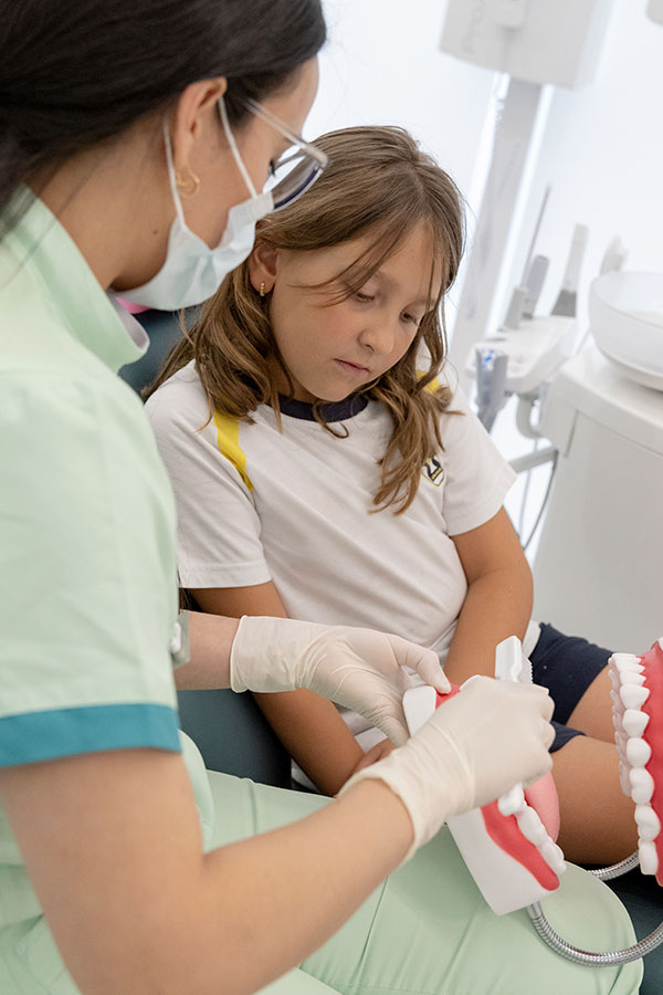 dentista infantil explicando tratamiento de higiene bucodental